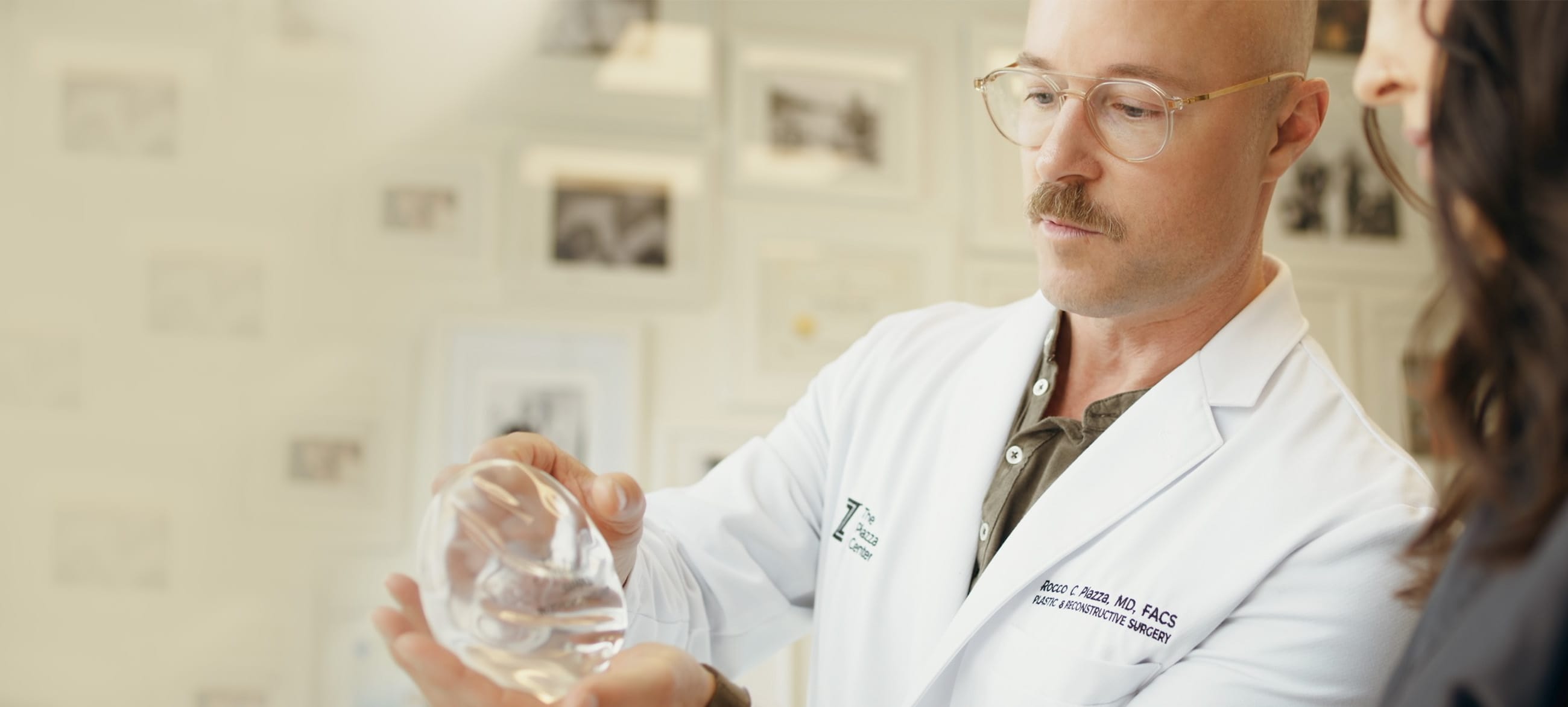 Dr. Rocco Piazza consulting with a patient, holding a breast implant, at The Piazza Center