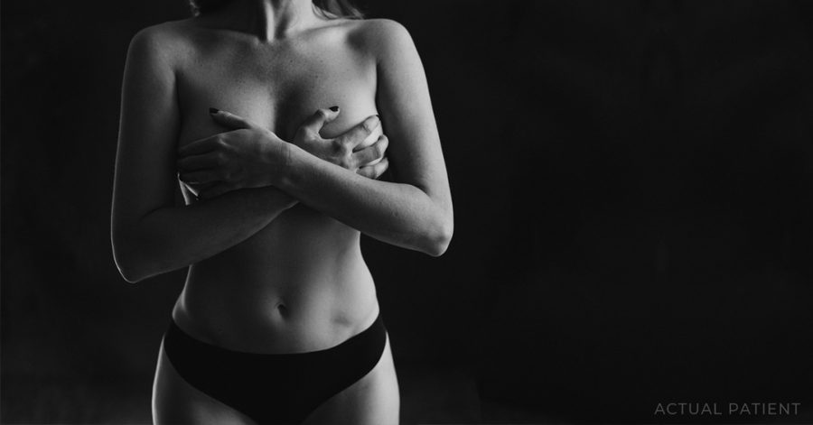 Black and white photo of a woman with hands on her breasts